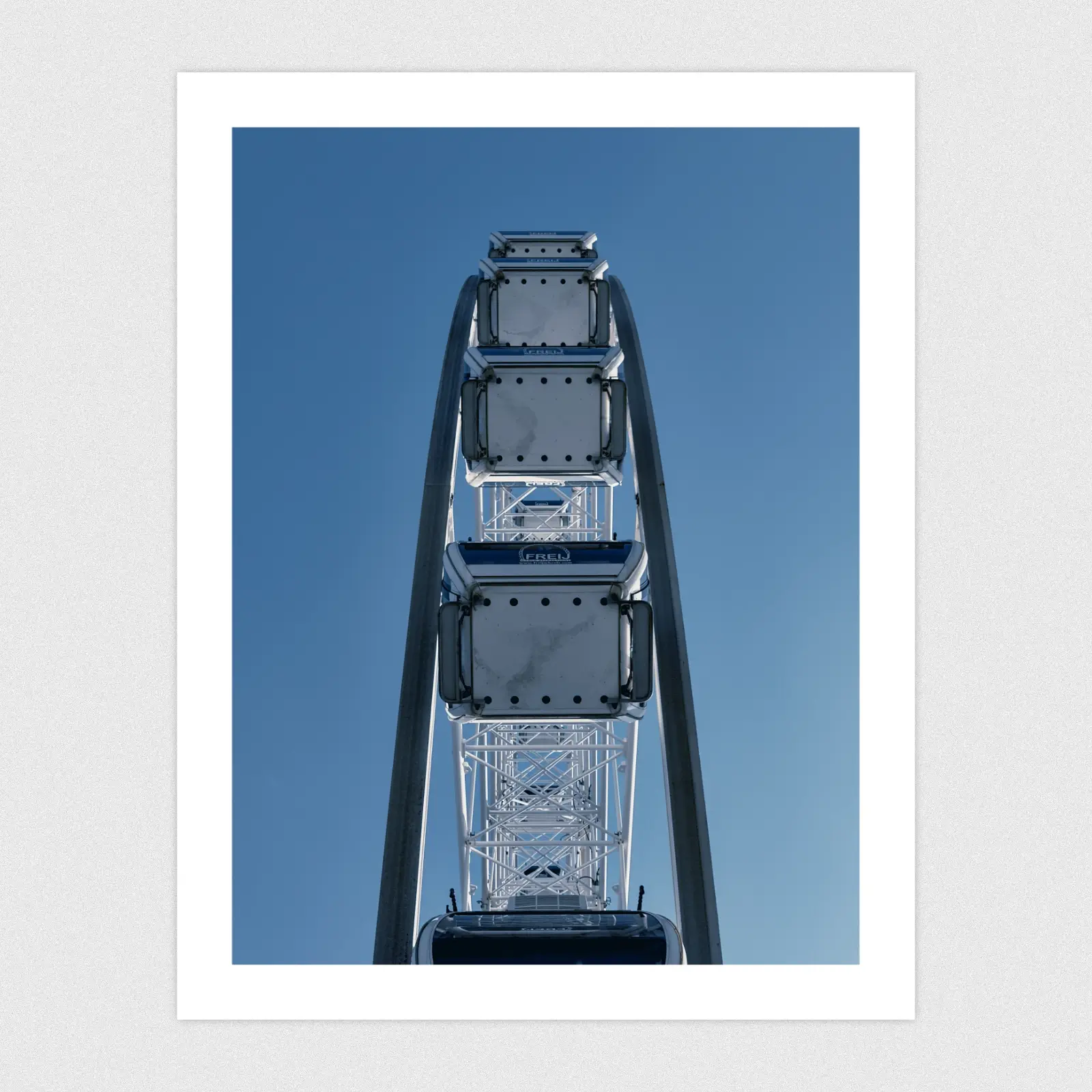 Portfolio Looking up from the centre of a big wheel with a blue sky background.