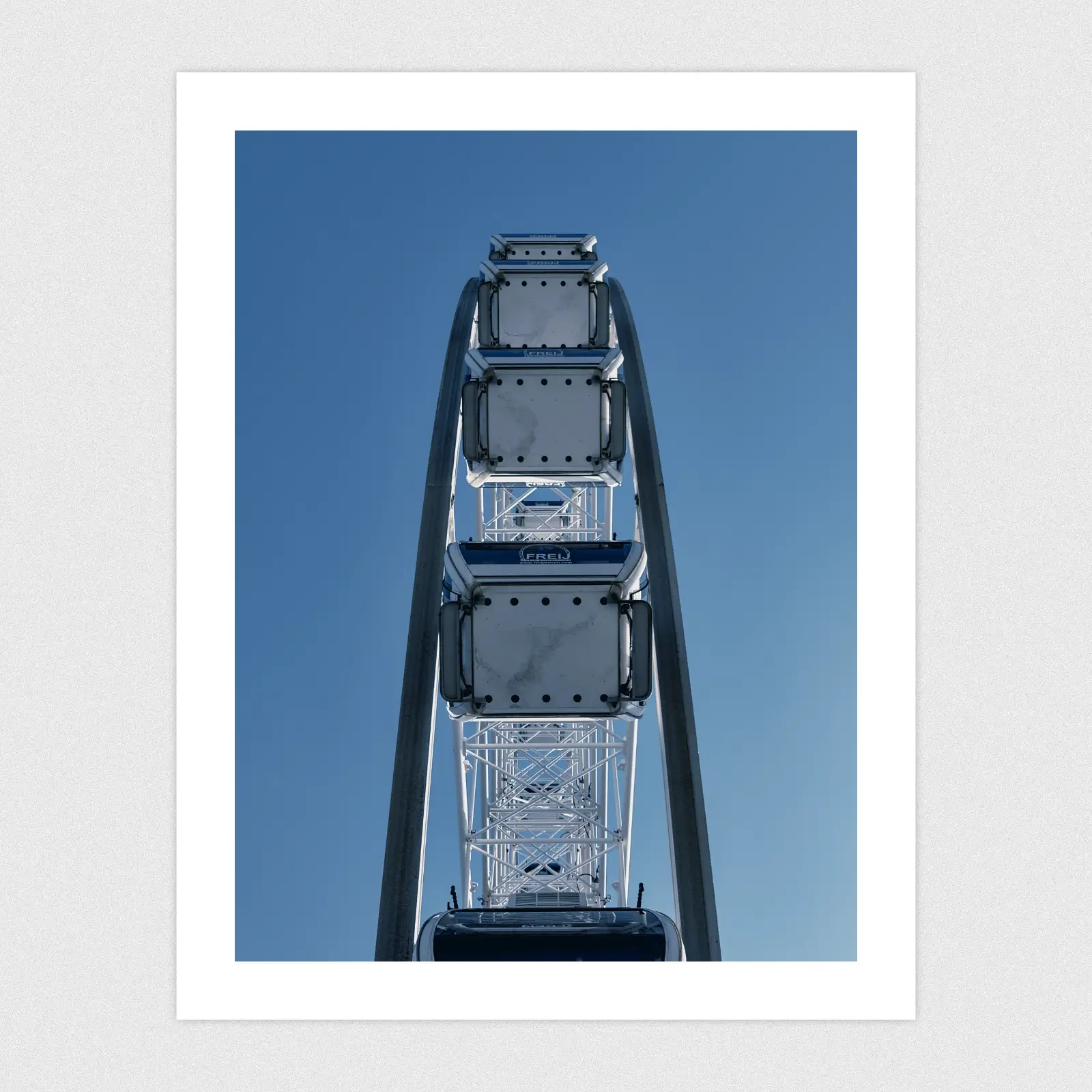 Portfolio Looking up from the centre of a big wheel with a blue sky background.