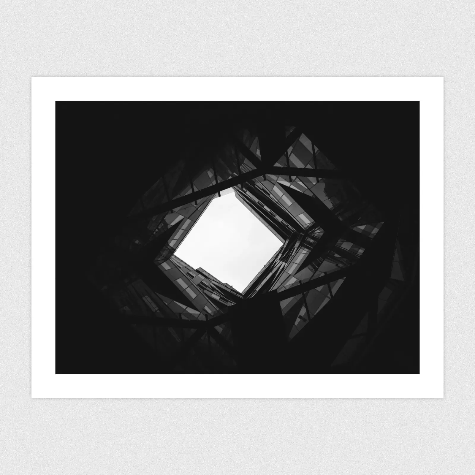 A black and white photo of the interior of a modern architecture building with an open ceiling/roof.