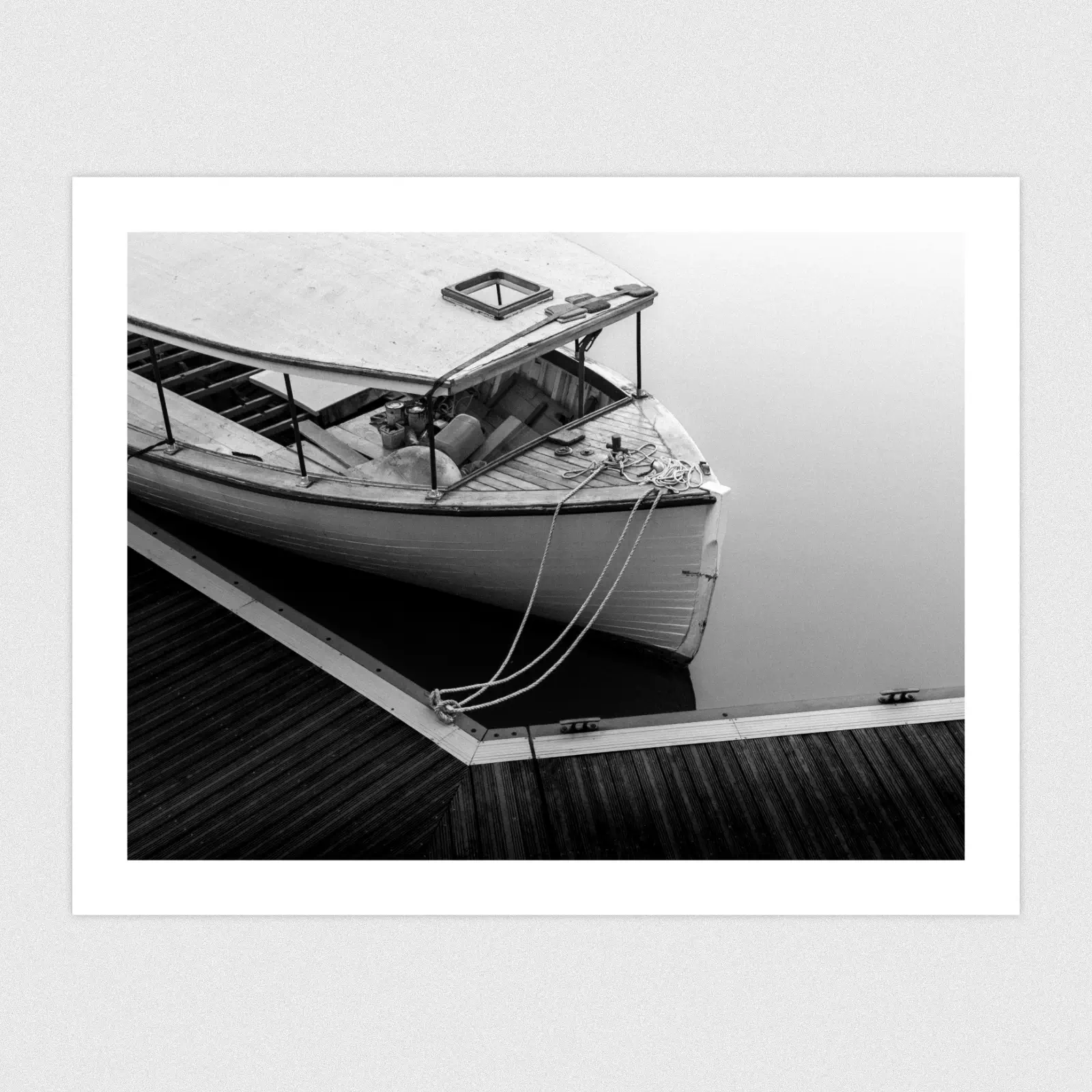 Portfolio A black and white photo a boat being renovated on perfectly still water.