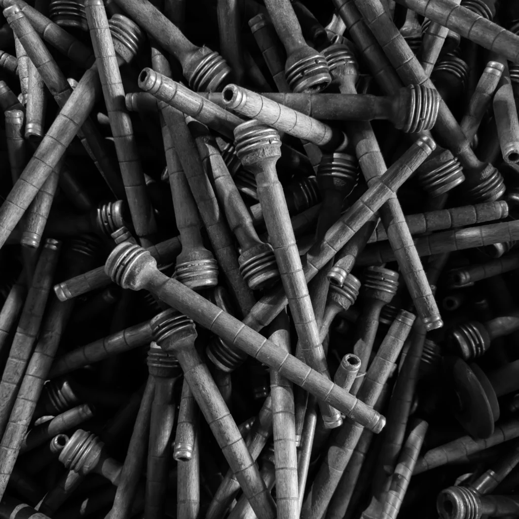 A black and white photo of a large pile of old wooden bobbins.