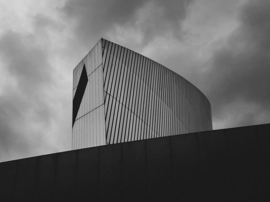 Black and white photo of modern architecture building with a moody sky background.