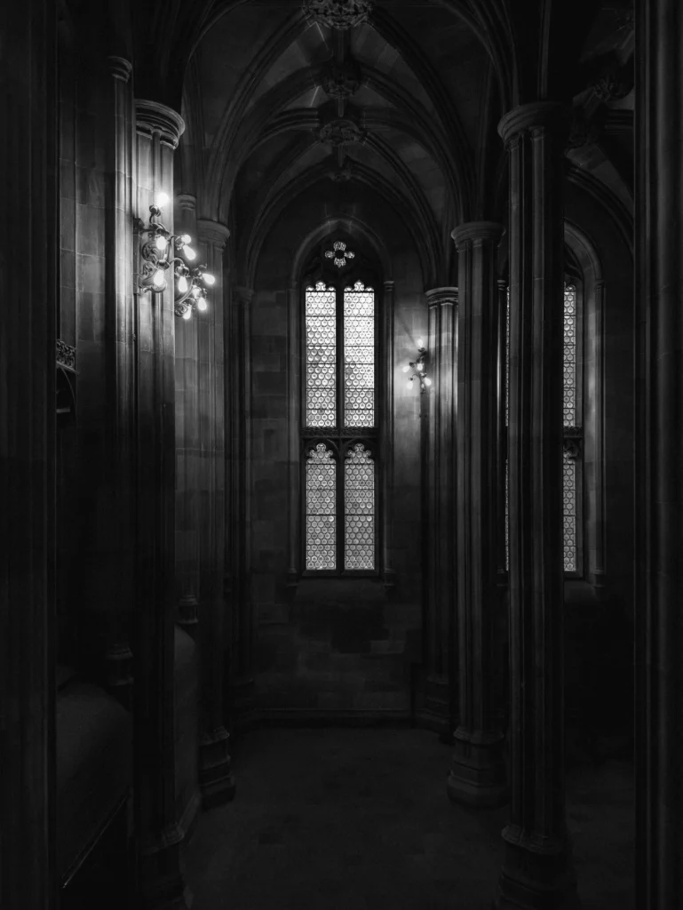 A dark interior of an old building with a window in the centre.