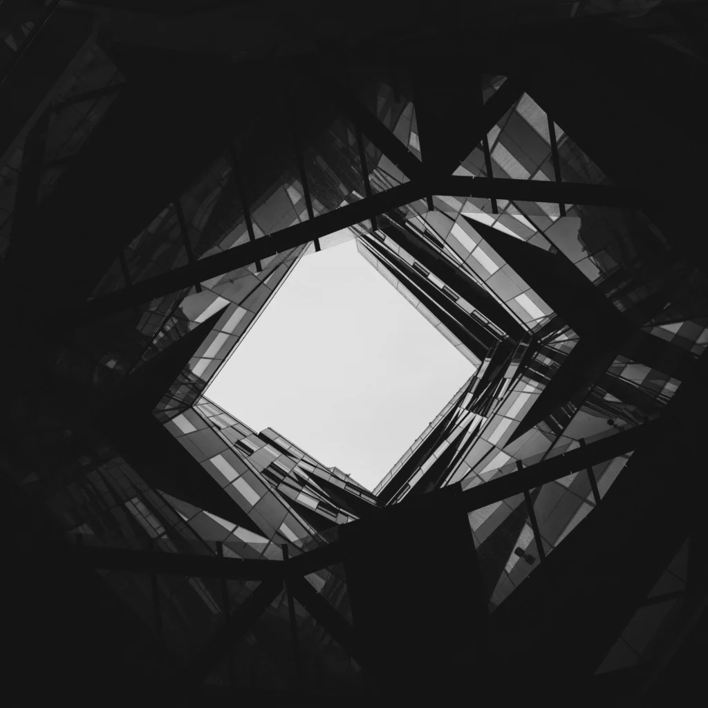 A black and white photo of the interior of a modern architecture building with an open ceiling/roof.