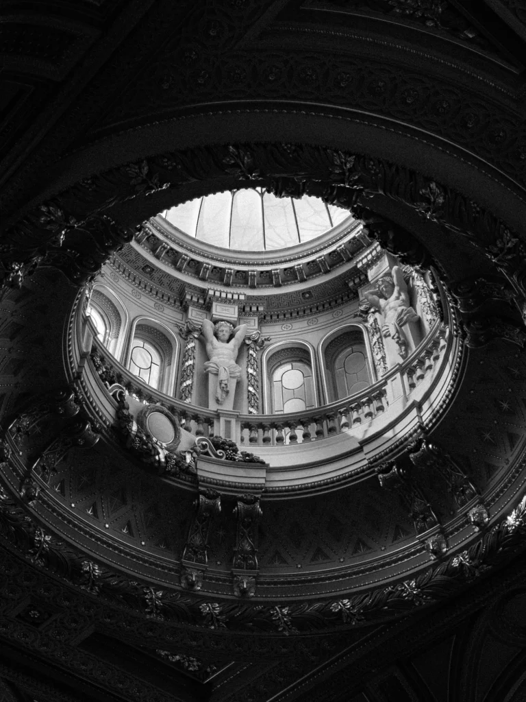 Black and white photo of a glass dome in an ornate ceiling.