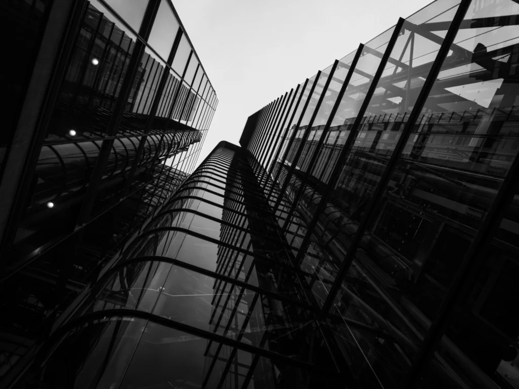 Black and white photo looking up at a modern, refelctive building.